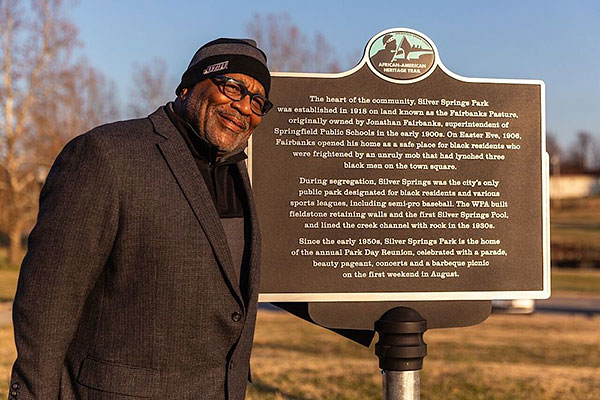 african american man standing next to a sign with historic information