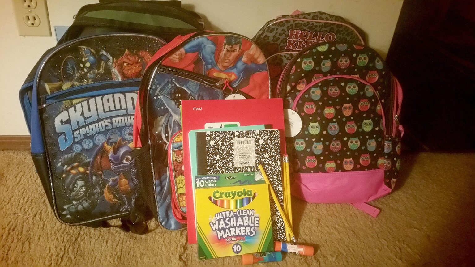 assortment of school backpacks with other school supplies in front